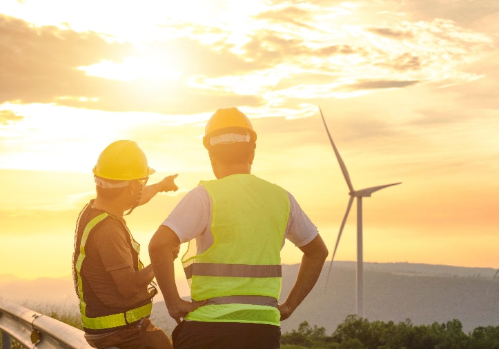 Two construction workers staring at a wind turbine